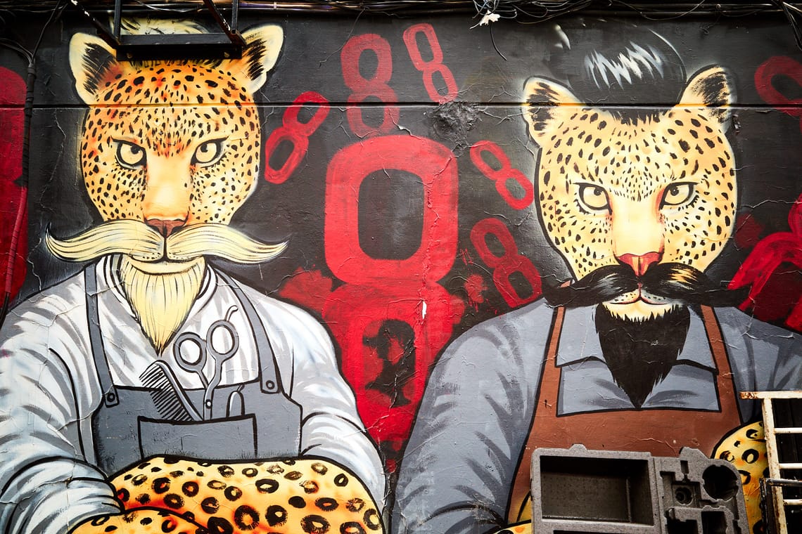 Peinture murale montrant deux léopards habillés en barbier et arborant de grandes bacchantes.