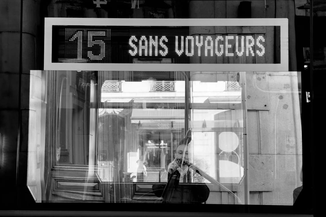 Reflet de l'auteur dans une vitre du tram sous l’affichage électronique indiquant "15 sans voyageurs »- Photo en noir et blanc.